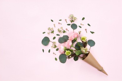 top view of floral composition of beautiful pink rose flower in kraft cornet on white background, flat lay, copyspace