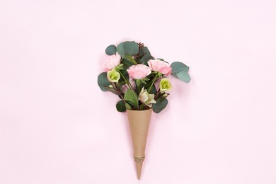 top view of floral composition of beautiful pink rose flower in kraft cornet on white background, flat lay, copyspace