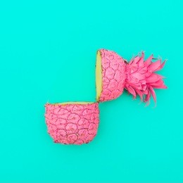 two painted in pink color halfs of the pineapple on turquoise background. minimalism and surrealism of food. flat lay  