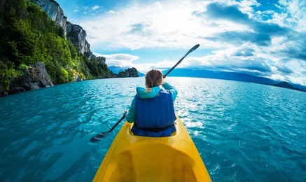 woman paddles kayak in the lake with turquoise water. patagonia, chile
