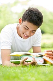 smiling student studying outdoors with books