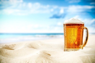 cold beer on sand and beach background 