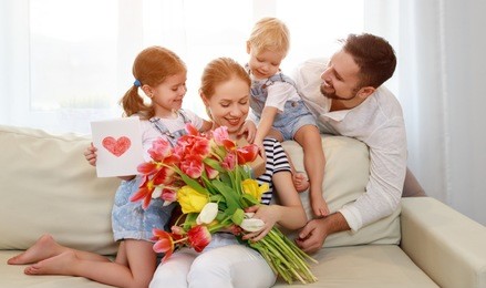 happy mother's day! father and children congratulate mother on holiday and give flowers
