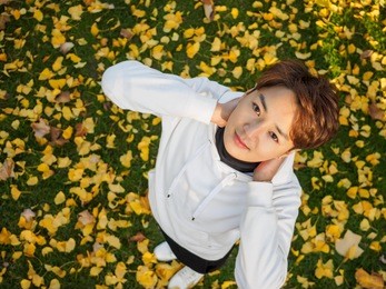 young chinese smiling man portrait stand with hands on his neck, high angle view, outdoor portrait.