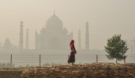 an asian woman visit taj mahal at early morning in misty day.