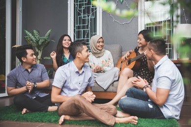 young happy friends having party, one playing guitar and the other singing together