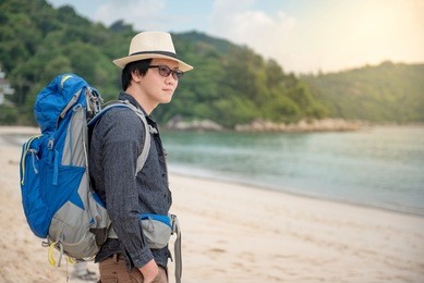 young asian man backpacker standing on the beach, summer holiday vacation and travel tropical island concepts