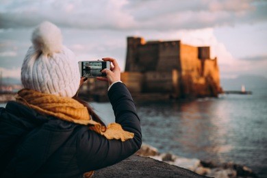 a tourist takes a picture of castel dell'ovo in naples, campania, italy.