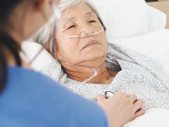 elderly asian woman laying on bed in hospital room.