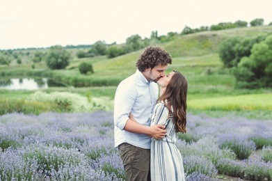a young couple is walking along the field with lavender.