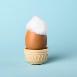 egg with soap foam in a waffle cookie for a cake, a creative idea on a colored background