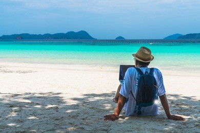 asian business man in summer vacation trip, traveler man relaxing on white sand beach using laptop, andaman sea, myanmar, southern of thailand, summer holiday outdoor vacation and travel trip
