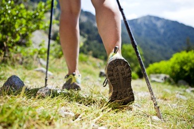 woman hiking in mountains, adventure and exercising. legs and nordic walking poles in summer nature.