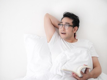 happy asian man reading a book on bed, man lifestyle on weekend concept.