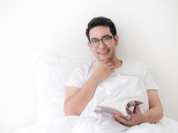 happy asian man reading a book on bed, man lifestyle on weekend concept.