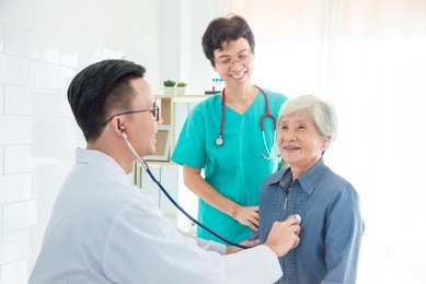 doctor checking patient's heartbeat by stethoscope at hospital
