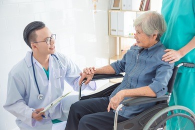 young asian doctor touching patient hand and smiles at hospital