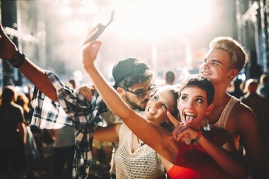 happy friends taking selfie at music festival