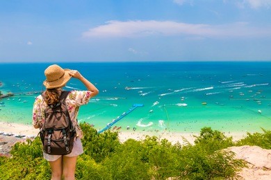 woman traveler with backpack and hat look at the sea beach and background from “koh larn“ in pattaya ,thailand. traveling thailand.