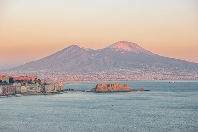panoramic view of the famous gulf of naples, with castel dell'ovo (egg castle) and the vesuvius on background at sunset