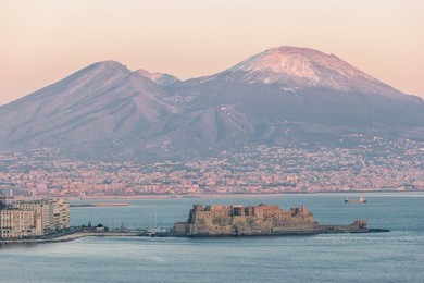 panoramic view of the famous gulf of naples, with castel dell'ovo (egg castle) and the vesuvius on background at sunset