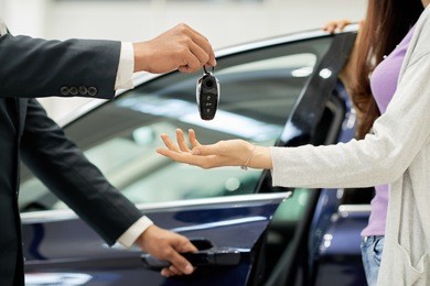 salesman giving key to female car buyer