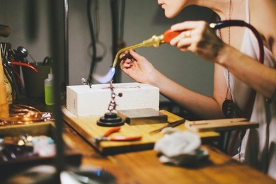 woman soldering and welding jewelry at workstation