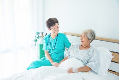 senior asian female patient smiling with nurse who come to visit her at bed
