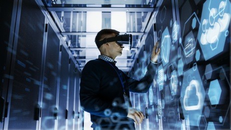 it engineer wearing virtual reality headset works with augmented reality software in data center. he wirelessly interacts with rack servers.