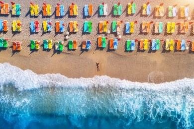 aerial view of lying woman on the beach with colorful chaise-lounges. beautiful young woman on the sea at sunset in oludeniz, turkey. top view. seascape with girl, azure water and waves. holiday