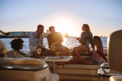 young rich friends drinking wine and beers in boat party during sunset. group of young people partying on yacht.
