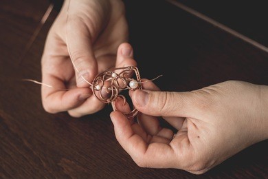 woman hands close up holding wire wrapped jewelry heart top view. woman hands close up making wire wrapped jewelry top view. st valentines holiday handicraft art artisan.
