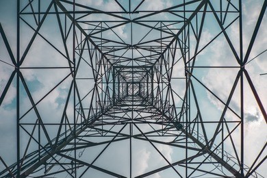 bottom perspective of truss structural of communication tower show the concept of symmetry of steel structure with blue sky in background.
