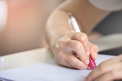 soft focus.high school or university student holding pencil writing on paper answer sheet.sitting on lecture chair taking final exam attending in examination room or classroom.student in casual