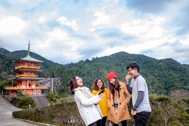 group of happy tourism gossip and laughing at sanjunoto pagoda with background of nachi waterfalls at kumano world heritage , wakayama , japan. group of young people looking at photo look so happy

