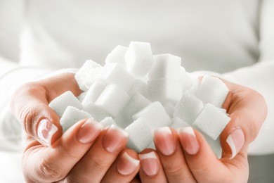 white sugar cubes in woman hands. woman holding pile of sugar in her hands. sugar close up.