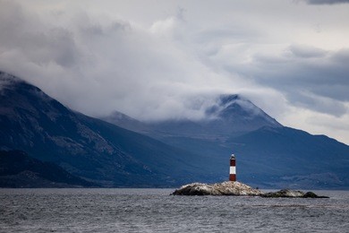 farol les eclaireurs, a red and white striped lighthouse on rocky island on the beagle channel, ushiaia, argentina