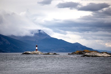 farol les eclaireurs, a red and white striped lighthouse on rocky island on the beagle channel, ushiaia, argentina