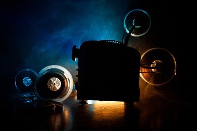 old style movie projector, still-life, close-up. film projector on a wooden background with dramatic lighting and selective focus. movies and entertainment concept