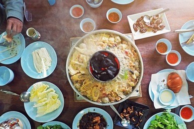 family enjoy eating traditional local asian chinese yunnan style grand hotpot on table center - photo take from top above view