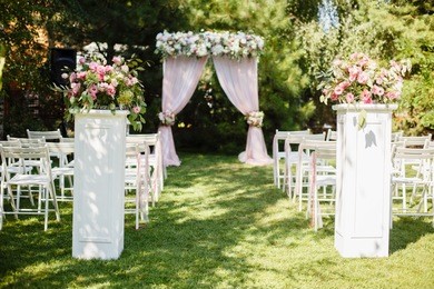 wedding ceremony in beautiful garden. elegant decoration of wedding ceremony in pretty pink colors. outdoors wedding ceremony with beautiful white furniture