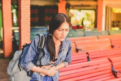 travel concept. beautiful girl is having severe stomach pain while traveling. asian women are not comfortable while traveling.