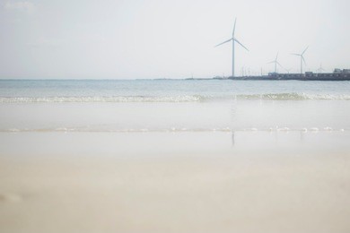 little wave on the beach with windmill. windmill reflected on the sea with blue sky.
