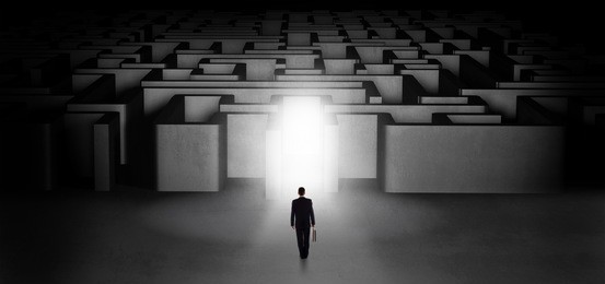 lost businessman standing at the dark labyrinth with illuminated door