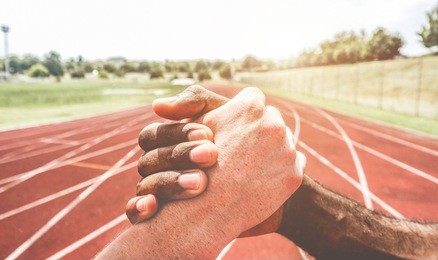 multiracial runners in a modern handshake to show each other friendship and respect against racism - fair competition and sport concept
