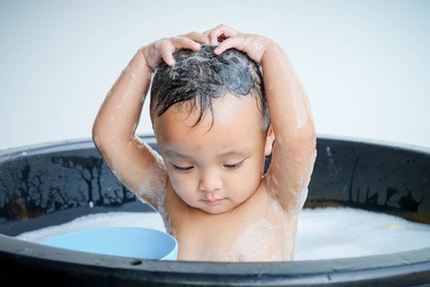 little asia child in a bathtub. infant washing and bathing. hygiene and care for young children.happy laughing thailand baby taking a bath playing with foam bubbles