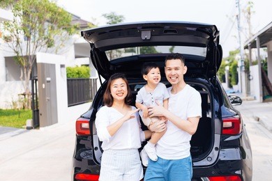 happy asian family standing on the back of suv car with smile and happiness