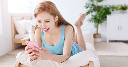 woman use phone happily and lying on sofa at home