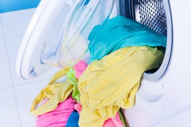 washing machine at bathroom, stainless drum inside with colored clothes.