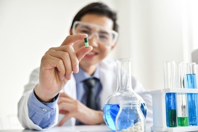 young male scientist holding a pill. asian male research is working in the laboratory. happiness.